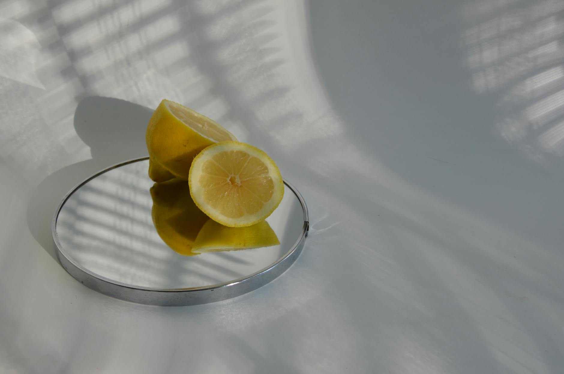 Limoni affettati su uno specchio con ombre minimaliste, rappresentando freschezza e chiarezza