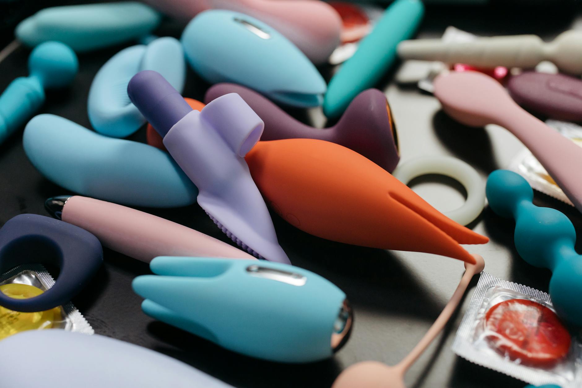 Una mano che tiene un vibratore arancione contro uno sfondo viola minimale, mostrando modernità e sensualità