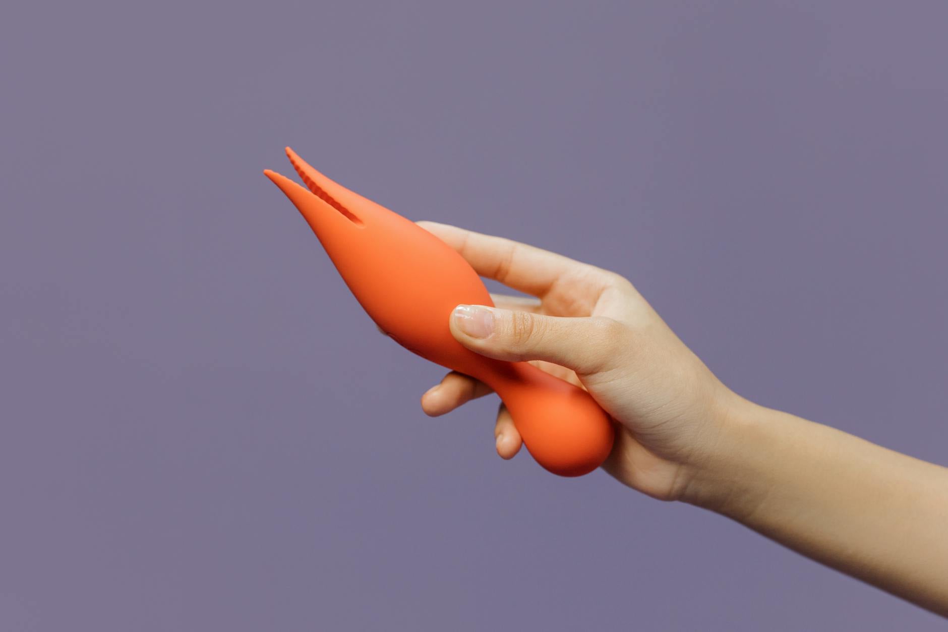 Una mano che tiene un vibratore al limone contro uno sfondo minimalista viola, mostrando la sensualità moderna