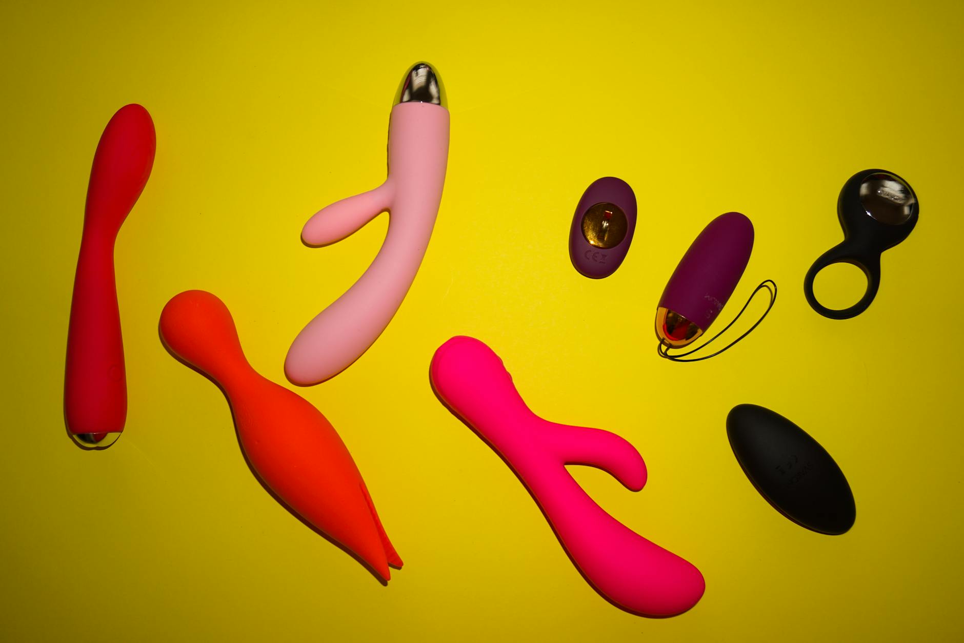 Close-up of hands holding a sleek lemon-colored vibrator against a purple background, intimate and tactile
